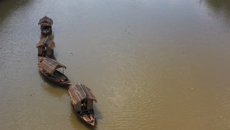 Aerial-view-of-a-line-of-four-small-traditional-Asian-fishing-boats-are-tied-up-in-a-canal-and-moving-with-flow-of-water-and-wind-Part-two-of-two