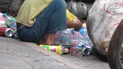 Niño-Camboyano-Sentado-Y-Clasificando-Latas-Y-Botellas-De-Plástico-En-Un-Saco