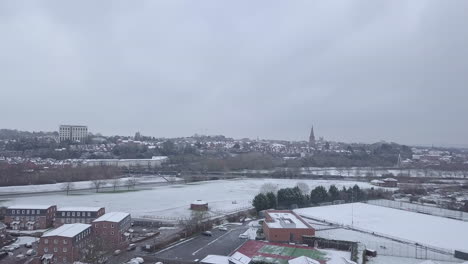 High-dolly-forward-drone-shot-of-a-snowy-Exeter-as-a-train-passes-by