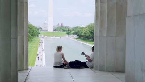 Paar-Sitzt-Vor-Dem-Lincoln-Memorial-In-Washington-D.C.-Mit-Blick-Auf-Den-Reflektierenden-Pool-Und-Das-Washington-Monument