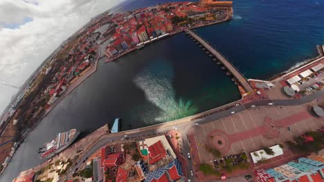 A-360-earth-globe-shot-of-Willemstad,-Curacao-waterfront-with-Queen-Emma-Bridge-on-St-Anna-Bay