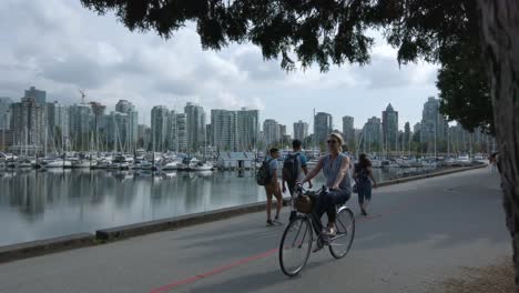Blick-Auf-Die-Landschaft-Im-Stanley-Park-Mit-Dem-Stadtzentrum-Von-Vancouver-Im-Hintergrund-Im-Sommer,-Tagsüber-Kommen-Viele-Menschen-Zum-Training-Und-Zum-Fahrradfahren