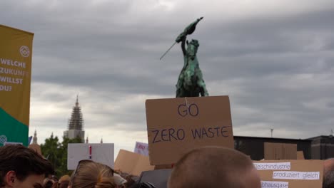 "Go-Zero-Waste"-Sign-being-held-up-high-during-fridays-for-future-climate-change-protests-in-Vienna,-Austria-SLOW-MOTION
