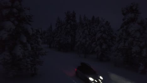 Car-driving-through-a-dark-forest-on-a-mid-winter-day-in-Finland