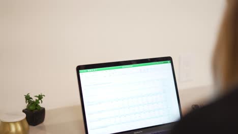 Frau-Tippt-Im-Büro-Auf-Laptop,-Rack-Fokus-Von-Der-Schulter-Zum-Computerbildschirm