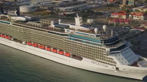 Aerial-close-up-view-of-the-bow-of-a-big-cruise-ship-in-dock-with-busy-streets-in-the-background