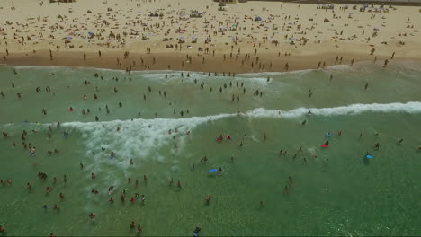 Drohnenaufnahme-Einer-Großen-Menschenmenge,-Die-Mitten-Im-Sommer-An-Einem-Heißen,-Klaren-Tag-Am-Bondi-Beach-Schwimmt