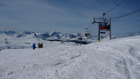 Chair-lift-at-ski-resort-on-snow-covered-mountain-with-skier-going-by