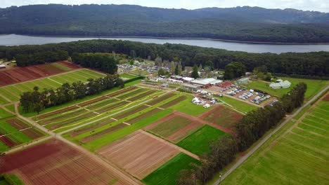Hovering-drone-view-of-the-Tesselaar-Tulip-Festival-with-Silvan-Reservoir-in-the-background,-Victoria,-Australia