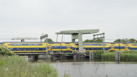 An-express-train-travels-slowly-over-a-bridge-in-Assendelft,-the-Netherlands
