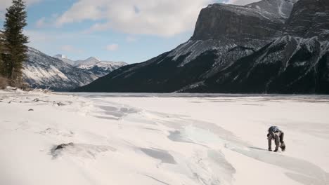 Chica-Excursionista-Disfruta-Deslizándose-Por-Losa-De-Hielo-En-Hermosas-Montañas-De-Invierno-En-El-Lago-Congelado-Minnewanka-En-El-Parque-Nacional-De-Banff,-Alberta,-Canadá,-En-Un-Día-Soleado-Al-Aire-Libre