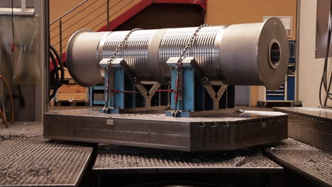 Rotating-big-metal-cylinder-chained-down-on-machine-at-workshop
