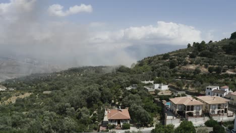 Forest-fire-smoke-on-the-edge-of-a-Spanish-village-with-trees-and-buildings,-no-people