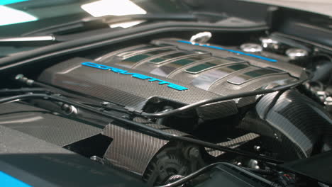 Bright-blue-text-on-carbon-fiber-engine-cover-on-modern-Chevrolet-Corvette,-Close-Up,-Slide-Left