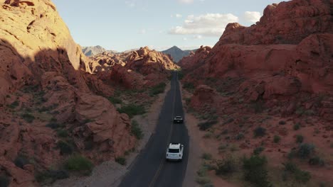 Aerial-push-in-on-a-Rolls-Royce-and-Ferrari-driving-on-an-open-highway-in-the-Valley-of-Fire,-Nevada