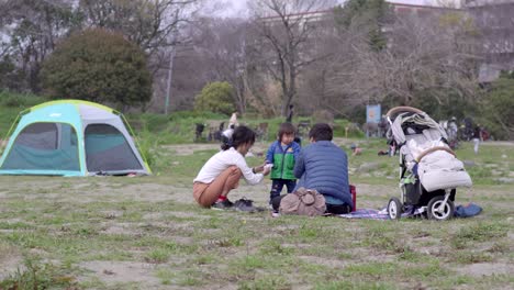 Una-Hermosa-Vista-De-Los-Jóvenes-Padres-Japoneses-Cuidando-A-Su-Hijo-Y-Divirtiéndose-En-El-Parque-Público-En-Japón