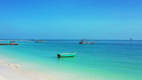 Paradise-sandy-beach,-turquoise-sea-and-fishing-boats-in-calm-lagoon