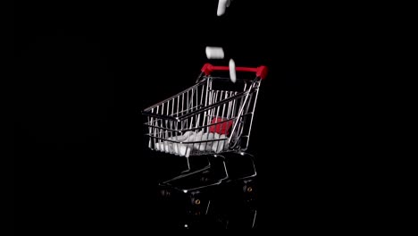 Sugary-chewing-gum-dropping-in-a-miniature-shopping-trolley