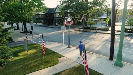 Pedestrian-walks-on-sidewalk-through-Small-Town-America-scene-decorated-for-4th-of-July