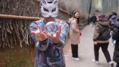 Masked-magician-performing-a-magic-trick-at-the-Arashiyama-Bamboo-Forest-in-Kyoto,-Japan