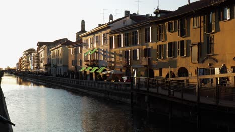 Milan-famous-Naviglio-Grande-canal-street-during-the-evening-at-golden-hour,-slow-pan-wide-shot