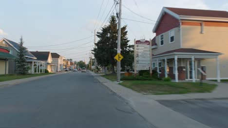 Car-driving-through-the-main-street-in-a-small-rural-village-in-Québec,-Canada