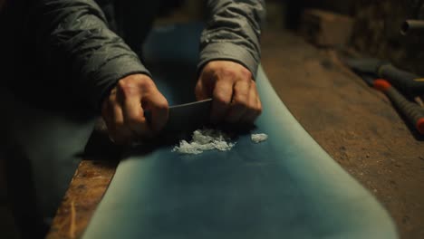 Close-up-scraping-wax-of-a-snowboard