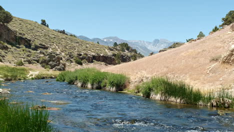 Coursing-River-Flowing-Through-Inyo-National-Forest-at-Hot-Creek-Geological-Site,-Blue-Sky-and-Sunshine,-Mountainous-Backdrop