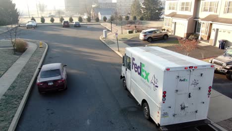 Door-to-door-parcel-delivery,-FedEx-Ground-van-in-street-of-residential-area,-express-delivery-service