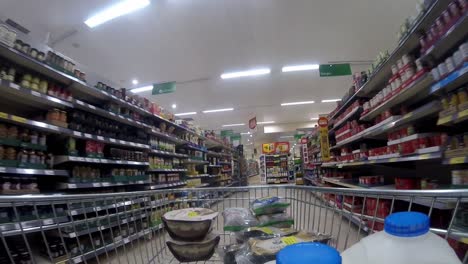 Inside-supermarket-shopping-cart-pushing-trolley-down-sauces-aisle-as-customers-shop-during-corona-virus-pandemic