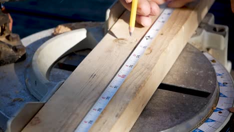 Close-Up-of-Carpenters-Hand-Pencilling-Marking-on-Circular-Metal-Measuring-Board