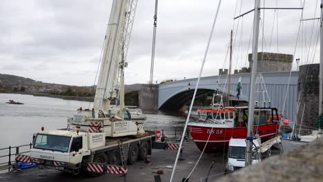 Hydraulic-crane-vehicle-lifting-fishing-boat-on-Conwy-Wales-harbour-lifting-boom-arm