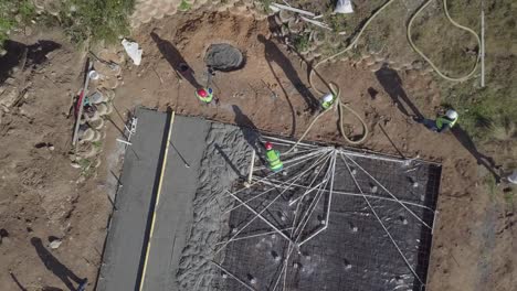 Rising-aerial-reveals-construction-crew-pouring-concrete-pad-for-home