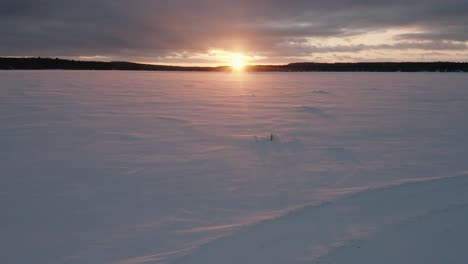 Wind-blows-across-the-snow-and-over-two-ice-fishing-traps-at-sunset-AERIAL