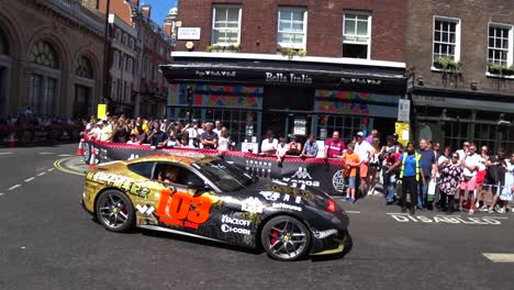 Luxury-motorsport-Gumball-3000-rally-parade-decal-wrapped-Ferrari-F12-driving-through-street-crowd-attraction