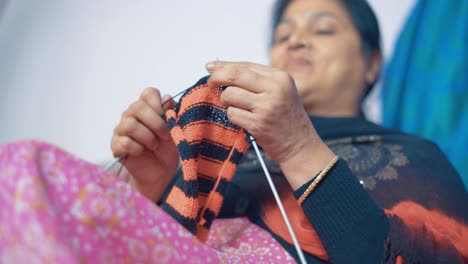 Indian-woman-knits-scarf-with-craft-needles-and-red-and-black-wool