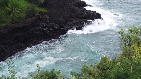 HD-120fps-Hawaii-Kauai-overhead-view-of-waves-crashing-on-rocky-shoreline-with-greenery-in-foreground