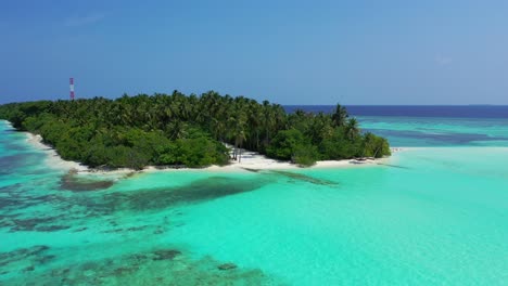 Idyllic-tropical-island-with-dense-palm-trees-forest-washed-by-calm-turquoise-lagoon-full-of-corals,-tall-communication-antenna-in-the-center-of-island-of-Caribbean