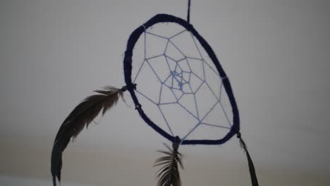 A-close-up-of-a-dreamcatcher-inside-a-dark,-abandoned-room-with-a-simple-white-backgorund-and-ceiling