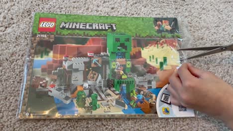 Kleine-Hände-Schneiden-Die-Plastikhülle-Von-Der-Anleitungsbroschüre-Seines-Neuen-Minecraft-Lego-Bausets-Ab