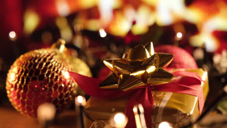 Goldenes-Weihnachtsgeschenk-Und-Rote-Kugeldekoration-Vor-Dem-Kamin-Im-Heimischen-Wohnzimmer