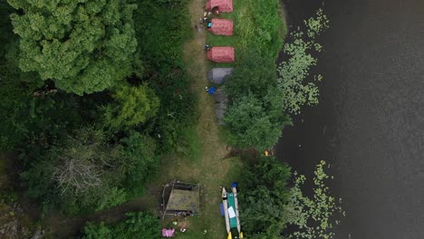 Luftaufnahme-Aus-Der-Vogelperspektive-Von-Menschen,-Die-In-Zelten-Im-Wald-Entlang-Eines-Flusses-Campen