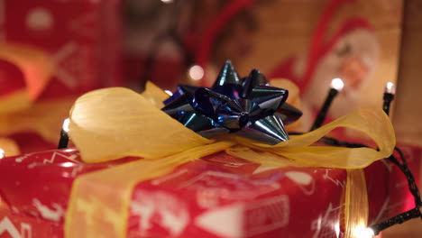 Weihnachtsgeschenke-Mit-Blauem-Band-Im-Heimischen-Wohnzimmer-Mit-Lichtern