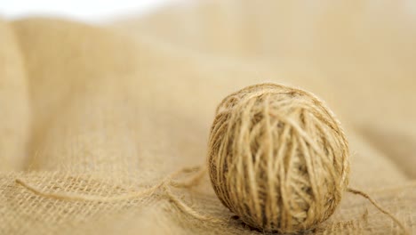A-Ball-Of-Jute-Dropping-Onto-A-Burlap-Hessian-Sack,-Natural-Fibre-Textile-Used-As-Twine