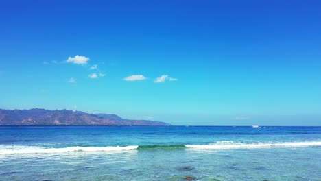 Paradiesische-Meereslandschaft-Mit-Weißen-Wellen,-Die-über-Felsigen-Meeresboden-An-Der-Küste-Einer-Tropischen-Insel-Mit-Hellblauem-Himmelshintergrund-In-Bali-Schäumen,-Kopierraum