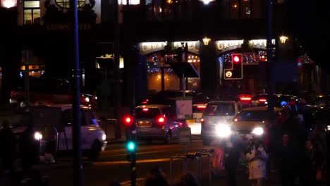 Uk-police-vehicle-driving-through-traffic-lights-at-night-in-busy-city-centre-junction