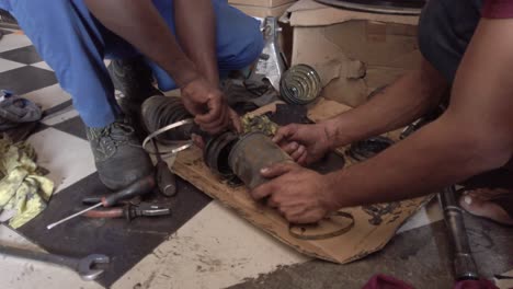 Mechaniker,-Die-An-Der-Achse-Eines-Autos-Arbeiten-Und-Versuchen,-Sie-Zu-Reparieren