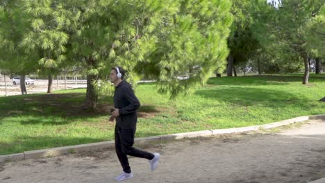 Man-looks-at-the-mobile-in-the-park-and-starts-jogging