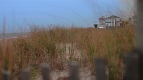 Fence-on-beach-with-grass-growing-in-sand-dunes,-Rack-Focus,-Slow-Motion