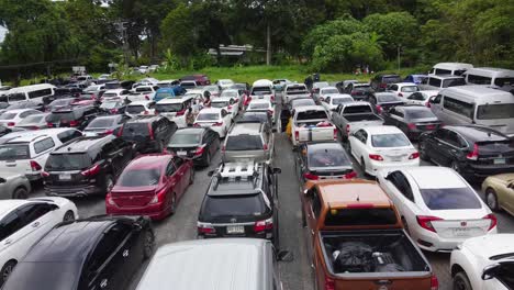AERIAL:-Drone-travels-forward-above-backs-of-cars-which-stuck-on-the-Parking-Zone-in-the-Queue-wait-for-Ferry-from-The-Koh-Chang-Island-to-Mainland-of-Trat,-Thailand,-Asia